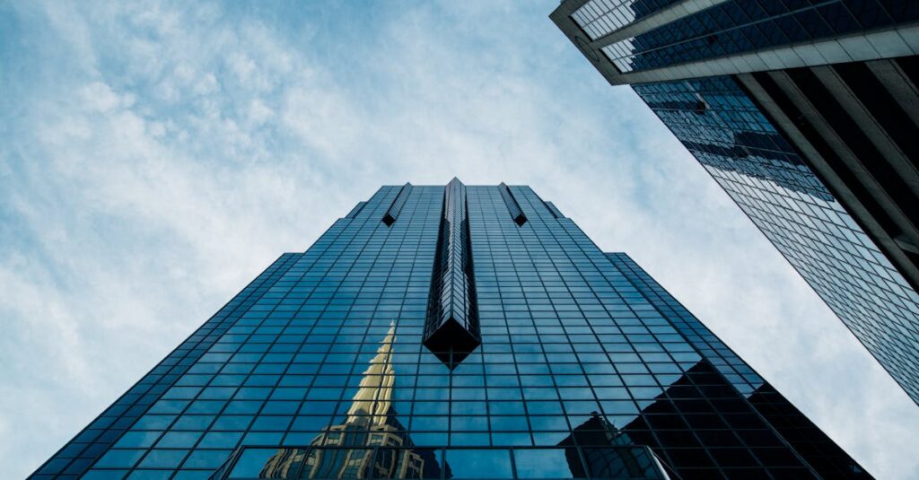 Low angle view of a modern skyscraper with reflective glass facade against a cloudy sky.